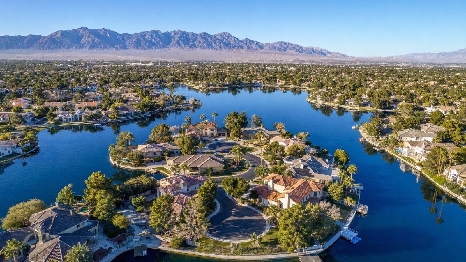 Las Vegas lakefront home with solar panels in a well-established residential community under a clear blue desert sky